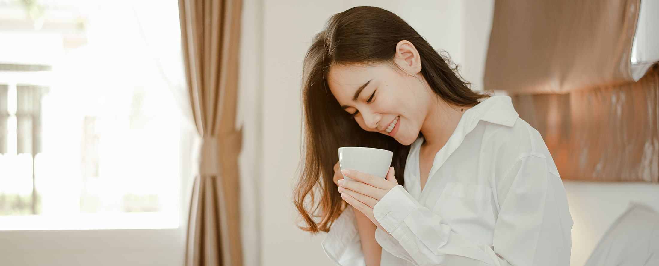 Young woman asia living at home relaxing and drinking cup of hot coffee in the bedroom on holiday. Asian, asia, relax, alone, technology, lifestyle concept.